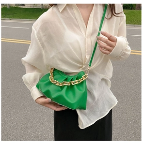 Detail of green ruched cloud bag showing gold chain strap and smooth PU leather texture