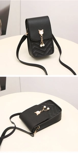 Macro view of black quilted crossbody bag featuring wave embroidery and pearl charm