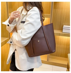 Close-up of a dark brown matte leather tote bag with a gold button front pocket