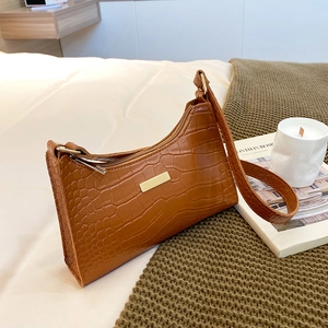 Brown crocodile embossed baguette bag with gold hardware on a cozy white blanket