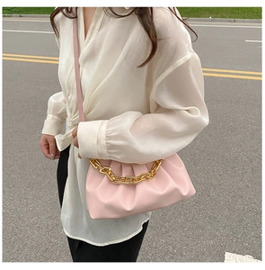Close-up of pink pleated cloud pouch bag with thick golden metal chain strap