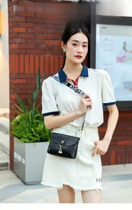 Detail of black crocodile texture mini bag with pearl charm and wide graphic strap