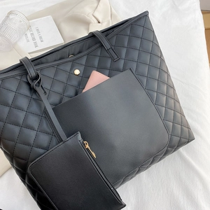 Quilted black tote bag set with inner pouch and gold hardware on white fabric