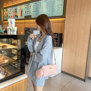 Pink quilted crossbody bag with small pouch and gold chain strap in a cafe setting