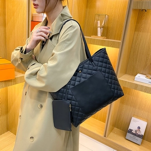 Black quilted rhombic tote bag set with matching pouch shown on shoulder in daily use