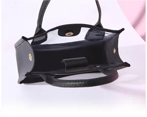 Detail view of the gold magnetic closure and interior space of the clear PVC handbag