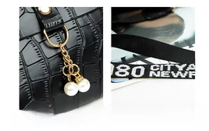 Detail of black crocodile texture bag with gold hardware, pearls, and wide logo strap