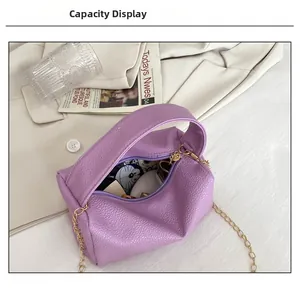 Detail view of purple pebbled leather handbag capacity showing cosmetics on a beige blazer