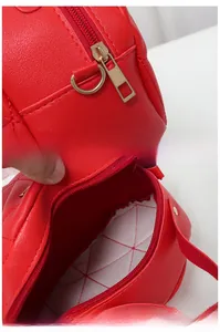 Detail of red quilted leather crossbody bag with metal zipper and spacious interior compartment