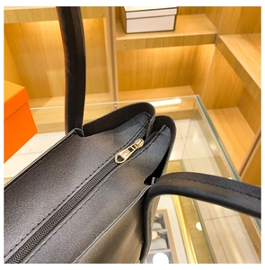 Detail of black pebbled leather tote bag with golden heart-shaped zipper puller