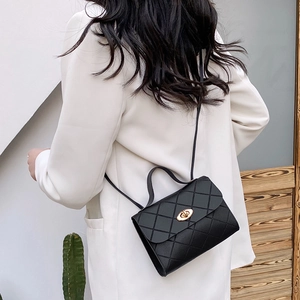 Sac à bandoulière noir matelassé avec fermoir doré dans un décor minimaliste moderne