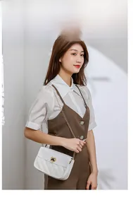 Close-up of white quilted crossbody bag featuring a golden heart-shaped metal twist lock