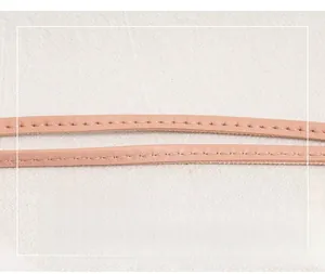 Close-up of pink leather shoulder strap with detailed stitching and refined texture