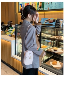 Sac à bandoulière rose matelassé avec charme de chat dans un café chaleureux