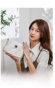 Detailed view of a white quilted chain bag with a gold heart-shaped metal buckle