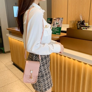 Pink quilted crossbody phone bag with pearl cat charm and wave stitching pattern