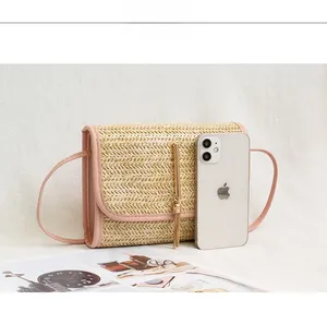 Detail of woven straw shoulder bag with pink faux leather trim and golden tassel