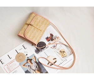 Detail of hand-woven straw crossbody bag with pink leather trim and golden metal bar clasp