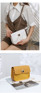 Detail of quilted crossbody chain bag featuring golden heart-shaped twist lock closure