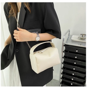 Macro shot of cream lychee-textured leather crossbody bag with elegant gold chain strap