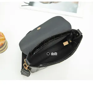 Detail of black crocodile texture mini bag interior with gold hardware and main compartment