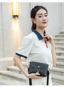 Detail of black croc-effect mini bag featuring gold hardware and a pearl charm accent