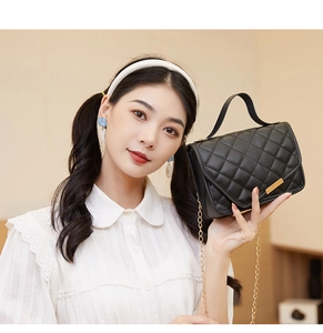 Detail of black quilted shoulder bag featuring gold chain strap and elegant metal buckle