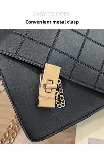 Close-up of golden rotating metal clasp on black quilted leather mini handbag with chain