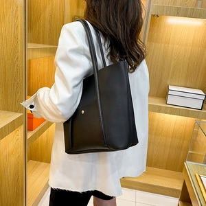 Classic black tote bag in matte PU leather with rivet details shown on model shoulder
