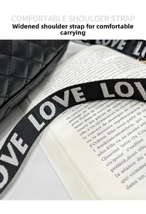 Dettaglio borsa trapuntata nera con ampia tracolla in tessuto e stampa di lettere LOVE