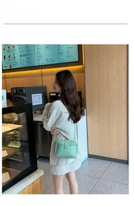 Détail du petit sac bandoulière vert clair en cuir avec texte FASHION et fermoir métal