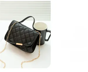 Detail of black quilted leather texture and gold metal chain on a crossbody bag