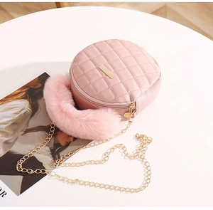 Sac rond matelassé rose avec poignée en peluche et chaîne dorée sur table blanche