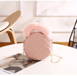Détail du sac rond rose matelassé avec poignée en fausse fourrure et chaîne dorée