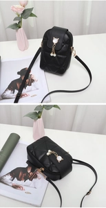 Détail d'un mini sac bandoulière noir avec breloques perles chat et motif matelassé