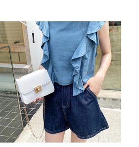 Détail d'un sac rectangulaire blanc avec bandoulière chaîne dorée et fermoir rotatif