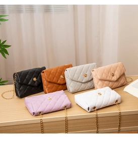 Detail view of quilted chain bags in six colors on a wooden surface with a gold flower lock