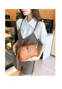 Brown quilted crossbody bag with metal clasp shown in a casual lifestyle setting