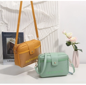 Détail de petits sacs carrés en orange et vert avec surface en cuir PU texturé de mode