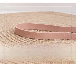 Close-up of pink leather shoulder strap with detailed stitching on a woven straw mat