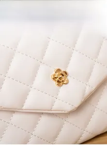 Detail of white quilted handbag with a golden camellia flower metal buckle close-up