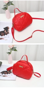 Detailed view of red quilted shell handbag with gold hardware and embroidery accents