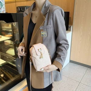 Elegante rosa gesteppte Umhängetasche mit Perlenanhänger, getragen von einem Modell im Café