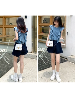 Détail du haut bleu à volants sans manches avec short en jean et sac à chaîne blanc