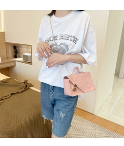 Pink quilted crossbody bag with gold chain strap shown on model in a modern room