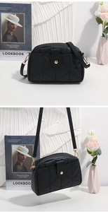 Detail of black crossbody bag with quilted triangle texture and gold round clasp