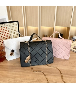 Chic quilted chain bags in white, black and pink on a wooden desk with a stylish backdrop