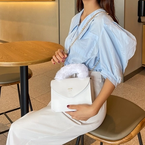 Chic white crossbody bag with plush faux fur handle and gold chain strap detail