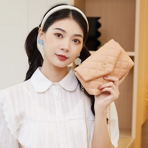 Quilted beige crossbody bag with gold camellia buckle and elegant metal chain strap