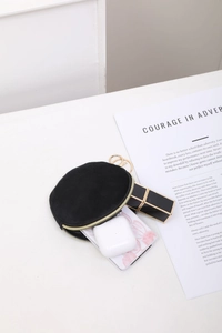 Vue détaillée du mini sac rond en daim noir avec fermeture éclair dorée pour cosmétiques
